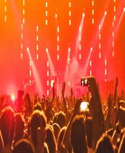 Concerto con luci rosse, pubblico esulta con le mani alzate.