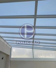 Cobertura de vidro em estrutura metálica branca, localizada numa área externa.