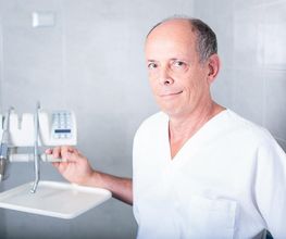 Dentista in camice bianco, accanto a strumenti odontoiatrici in studio dentistico.