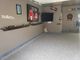 Garage with decor, TV, dartboard, and "Mr & Mrs" sign on gray walls, and a speckled floor.