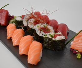 Plato de sushi variado con nigiri de salmón y atún. Decorado con cebollino y hilos de chile rojo.