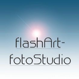 Textlogo vor blauem Hintergrund: "flashArt-fotoStudio" mit Lichtreflexion im Hintergrund.
