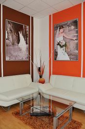 Weißes Sofa mit Glastisch, umgeben von orangen und braunen Wänden mit Hochzeitsfotos.