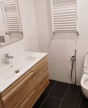 Baño moderno con lavabo, espejo, inodoro y azulejos blancos.
