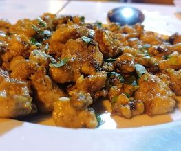 Plato de comida con trozos de carne dorados y limón en una mesa.