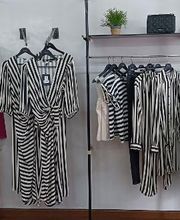 Vestidos y camisas de rayas blancas y negras colgados en un perchero en una tienda.