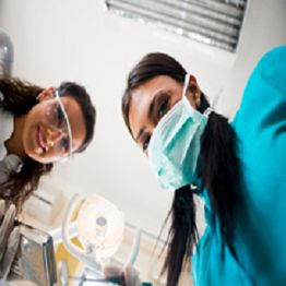 Dental professionals wearing masks, looking down from above.
