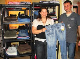 Personen halten Jeans in einem Bekleidungsgeschäft, umgeben von Regalen mit gefalteten Kleidungsstücken.