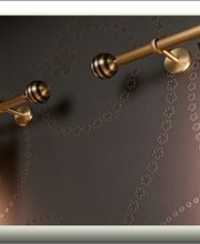 Goldene Vorhangstange mit braunen Vorhängen vor einer dunkelgrauen gemusterten Wand.