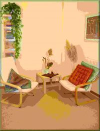 Due poltrone con cuscini attorno a un tavolino; piante e libri sullo sfondo. Ambiente accogliente.