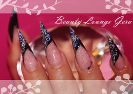 Nahaufnahme von aufwendigem Nageldesign mit schwarzen Spitzen und blauen Verzierungen.