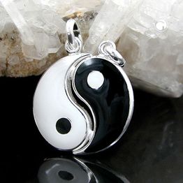 Yin-Yang-Anhänger aus schwarzem und weißem Material, liegend auf einem Kristallhintergrund.