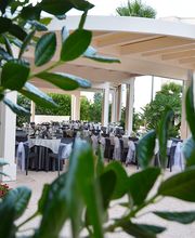 Gazebo elegante con tavoli apparecchiati, visto tra le foglie di un cespuglio.