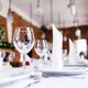 Elegant table setting with folded napkins and wine glasses in a warmly lit room.