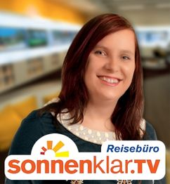 Eine lächelnde Frau steht in einem Reisebüro. Unten ist das Logo von sonnenklar.TV zu sehen.