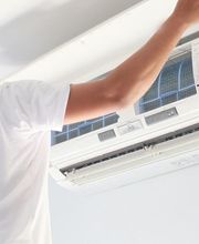 Persona reparando un aire acondicionado en la pared.