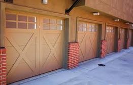 Row of brown garage doors with brick pillars on a sunny day.