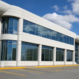 Modern office building with large glass windows under a blue sky.