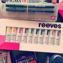 Art supplies including marker pens, colored paints, and assorted pencils are displayed together.