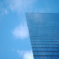 Glass skyscraper against a clear blue sky with few clouds.