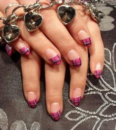 Nägel mit rosa-schwarz kariertem Design, Hände mit silbernem Herzarmband auf Blumenstoff.