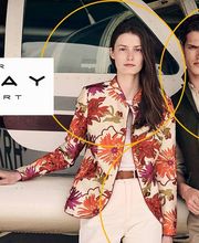 Zwei Models posieren stilvoll vor einem Flugzeug. Text: "Verbier Fellay Mode & Sport."