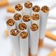 Close-up of upright cigarettes showing brown tobacco, with blurred cigarettes in the background.