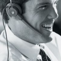 Lächelnder Mann mit Headset im Büro, Nahaufnahme in Schwarz-Weiß.