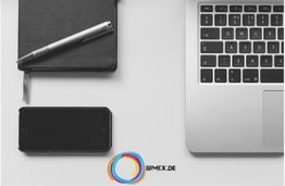 Laptop, Smartphone, Notizbuch und Stift auf einem weißen Tisch, Logo unten in der Mitte.