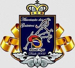 Brasão da Associação dos Gaiteiros com instrumentos e faixa dourada, texto: "Desde 2002".