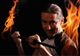 Mann mit Feuerstab, der Flammen in beide Hände hält, in einer dynamischen Pose vor dunklem Hintergrund.