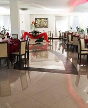 Sala ricevimenti elegante con tavoli rotondi apparecchiati, decorazioni rosse e pavimento lucido.