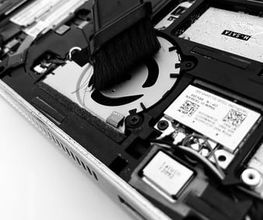 Laptop-Innenleben wird mit einem Pinsel gereinigt. Schwarz-weiße Nahaufnahme.