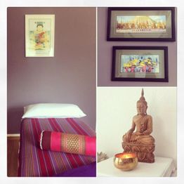 Raum mit Massagebett, Buddha-Statue, Kerze und Wandbildern in ruhiger, entspannender Atmosphäre.