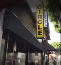 Building facade with signs for "Circle Cocktails" and "Bar." Trees in the background.