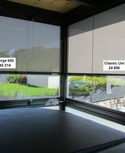 Blick aus einem Fenster mit zwei verschiedenen Jalousienmodellen: „Sergé 600“ und „Classic Uni“.