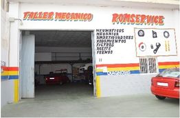 Taller mecánico Romservice con autos rojos en el interior y lista de servicios en la pared.