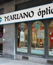 Óptica "Mariano Óptico" con escaparate en la calle, mostrando productos y decoración interior.