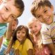 Group of smiling children looking down toward the camera on a sunny day.