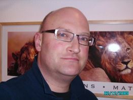 Mann mit Brille vor einem Löwenbild, Datum im Bild: 02.12.2009.