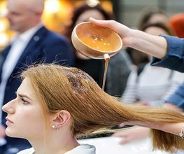 Donna riceve trattamento per capelli con liquido versato da una ciotola.