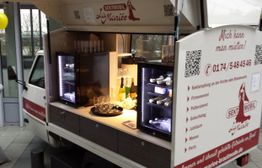 Kleiner weißer Wagen mit Bar, Kühlschränken und Getränken, gestyled als mobiles Sektauto.