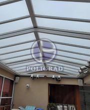 Teto de vidro em varanda coberta, com cadeiras e iluminação instalada.