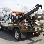 Tow truck with lifting equipment parked outdoors.