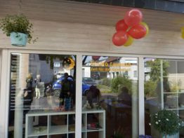 Ladenfront mit roten und gelben Ballons und Topfpflanzen. Reflexionen im Fenster sichtbar.