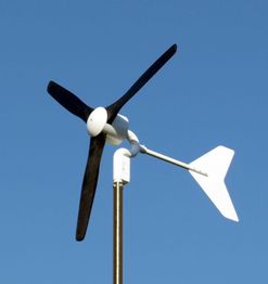 Kleine Windturbine mit drei Rotorblättern und blauem Himmel im Hintergrund.