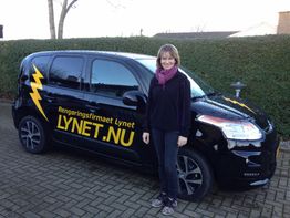 En kvinde står ved siden af en sort bil med teksten "Rengøringsfirmaet Lynet" og "LYNET.NU".