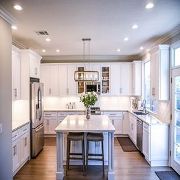 Modern kitchen with white cabinets, island, stainless steel appliances, and pendant lighting.