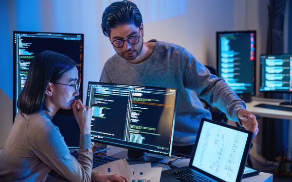 Zwei Entwickler betrachten Bildschirm mit vielen verschieden Codes