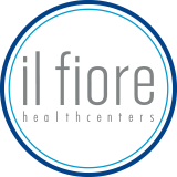 Logo met tekst "il fiore healthcenters" in grijs binnen een witte cirkel met blauwe rand.